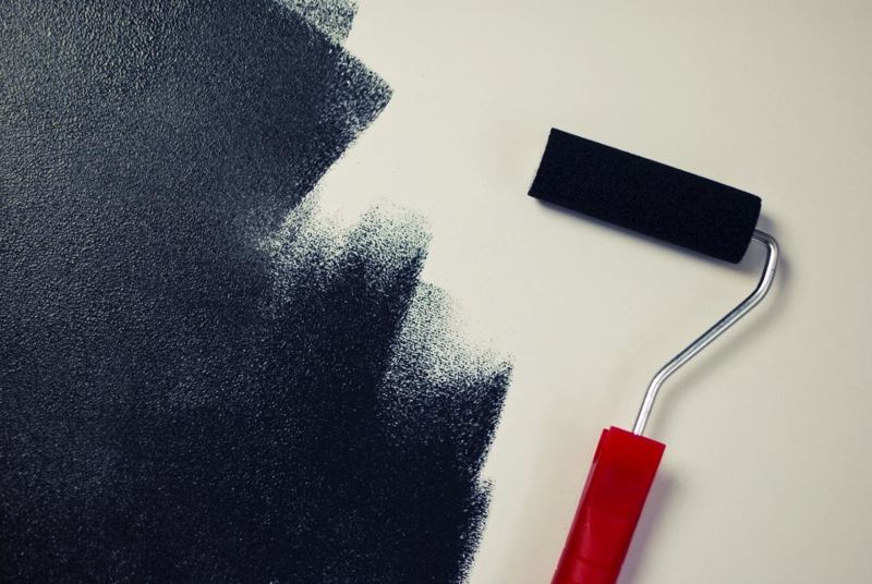 Paint roller on a freshly painted wall
